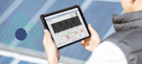 Mann, mit Rugged Tablet, mit Messwerten eines automatisierten Prüfablauf vor Solarpanels