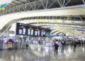 Großes, modernes Flughafenterminal mit Check-in-Schaltern, Passagieren und digitalen Anzeigetafeln – relevanter Ort für Indoor Funkvermessung zur Netzoptimierung