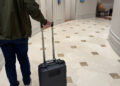 Person mit mobilem Messkoffer für Indoor Funkvermessung vor Aufzügen in einem modernen Hotel oder Bürogebäude – Funknetz-Analyse in Empfangsbereichen