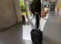 Person mit mobilem Messkoffer für Indoor Funkvermessung in einem modernen Büro- oder Bildungsgebäude mit Tageslicht und Glasfassade.